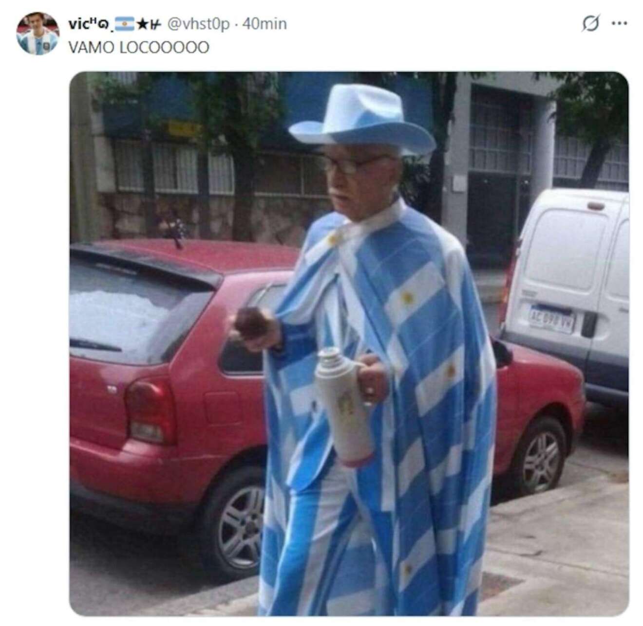 Hombre vestido con una capa argentina y sombrero, sosteniendo un termo en la calle