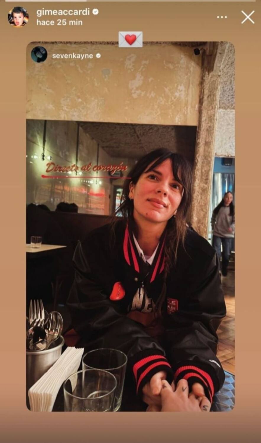 Gime Accardi sonríe mientras sostiene la mano de Seven Kayne en un ambiente acogedor