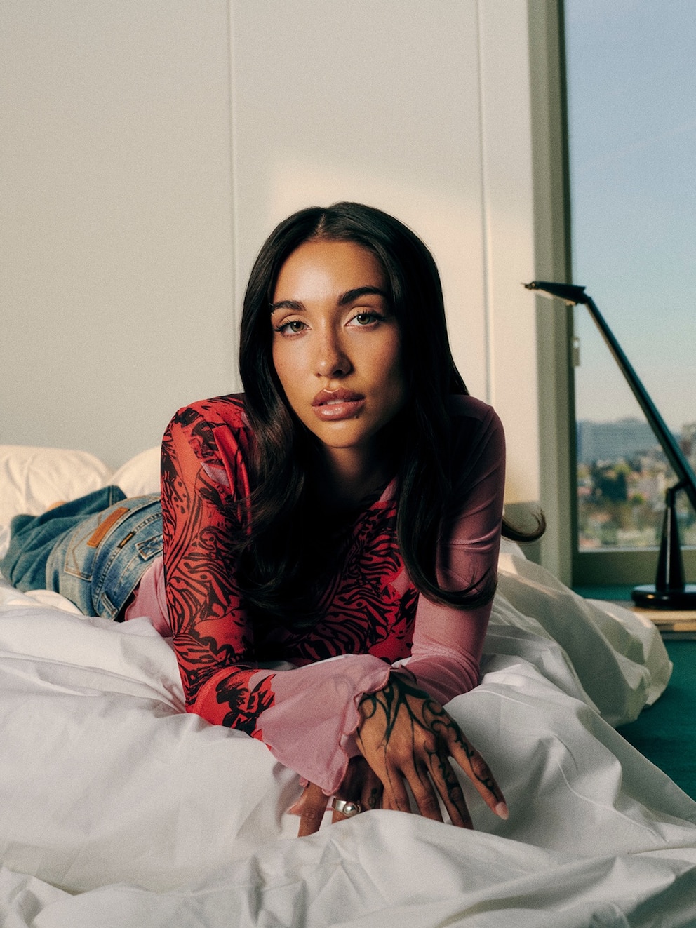 María Becerra posando en una cama con un atuendo de moda en una campaña para El Corte Inglés